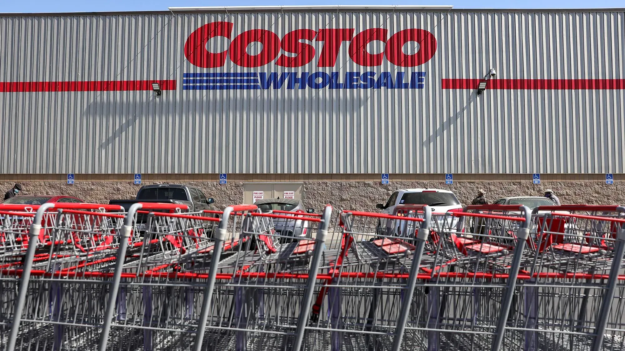 مدخل متجر كوستكو مع شعار الشركة واضحاً، بينما تُركت عربات التسوق الحمراء متراصة في الجهة الأمامية.