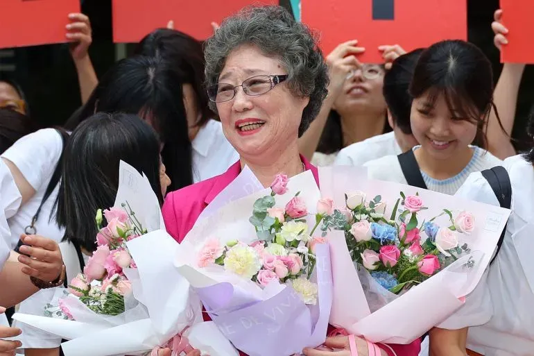 تشوي مال-جا، امرأة في السبعينيات من عمرها، تحمل باقات من الزهور بينما تحتفل مع مؤيديها بعد تبرئتها من تهمة الدفاع عن النفس.