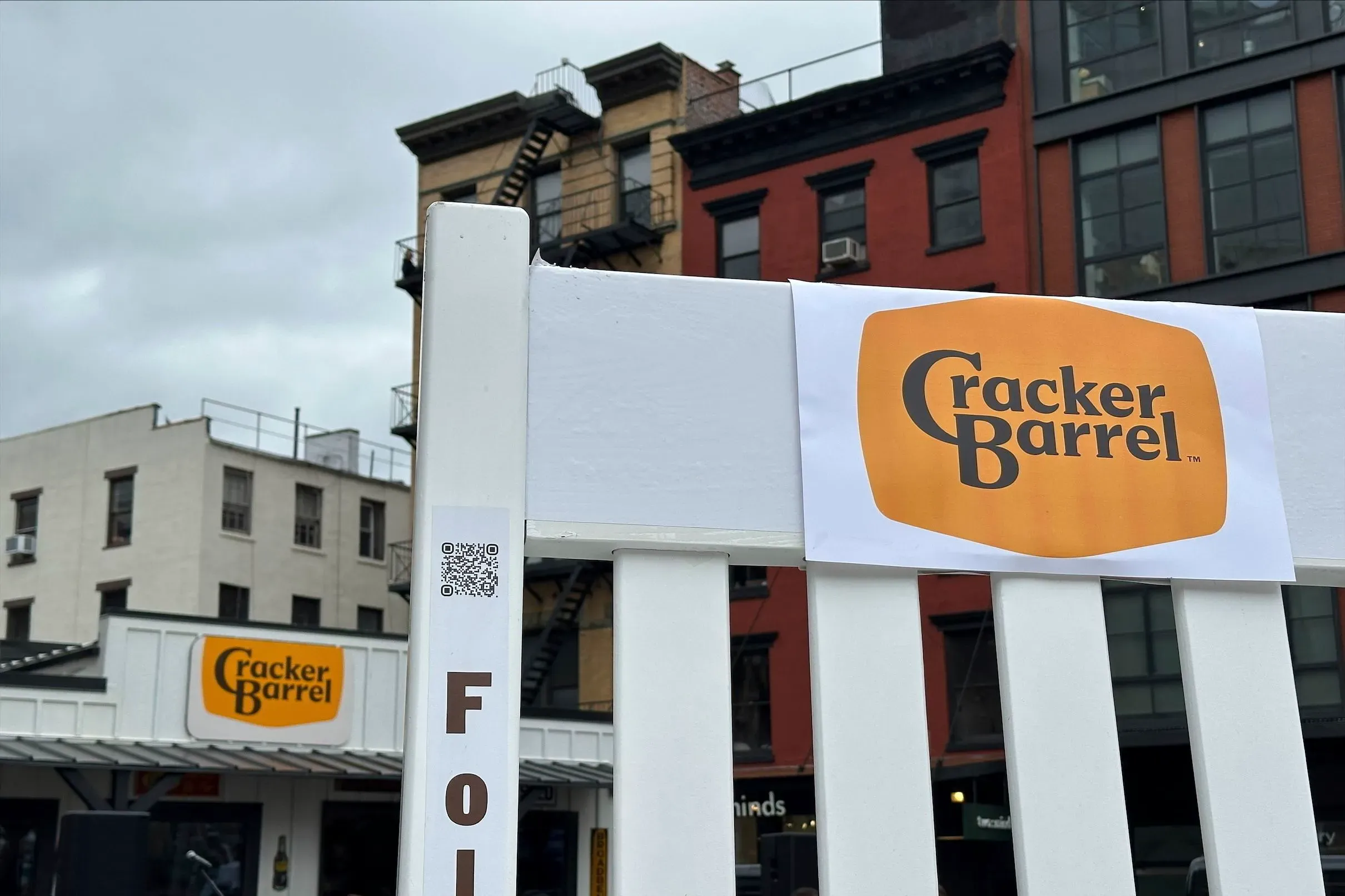 شعار كراكر باريل الجديد معلق على سياج أمام المطعم، بينما يظهر المبنى الخلفي في المدينة، بعد ردود فعل سلبية على التصميم.