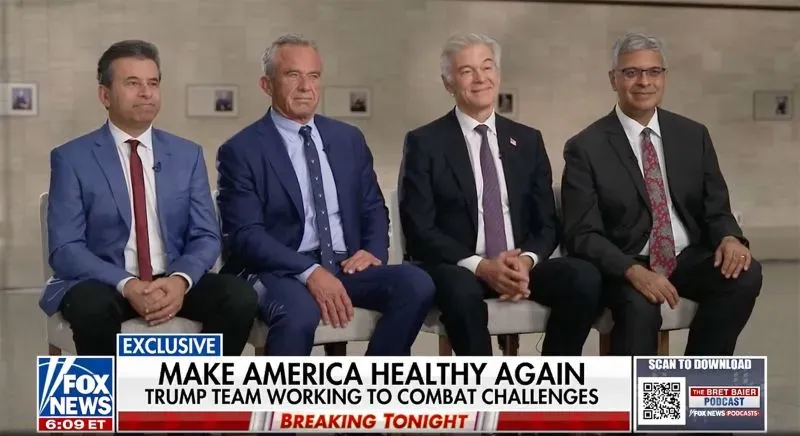 أربعة رجال يجلسون معًا في قاعة احتفالات، يتحدثون عن قضايا الصحة العامة والمبادرات الجديدة تحت شعار "اجعلوا أمريكا صحية مرة أخرى".