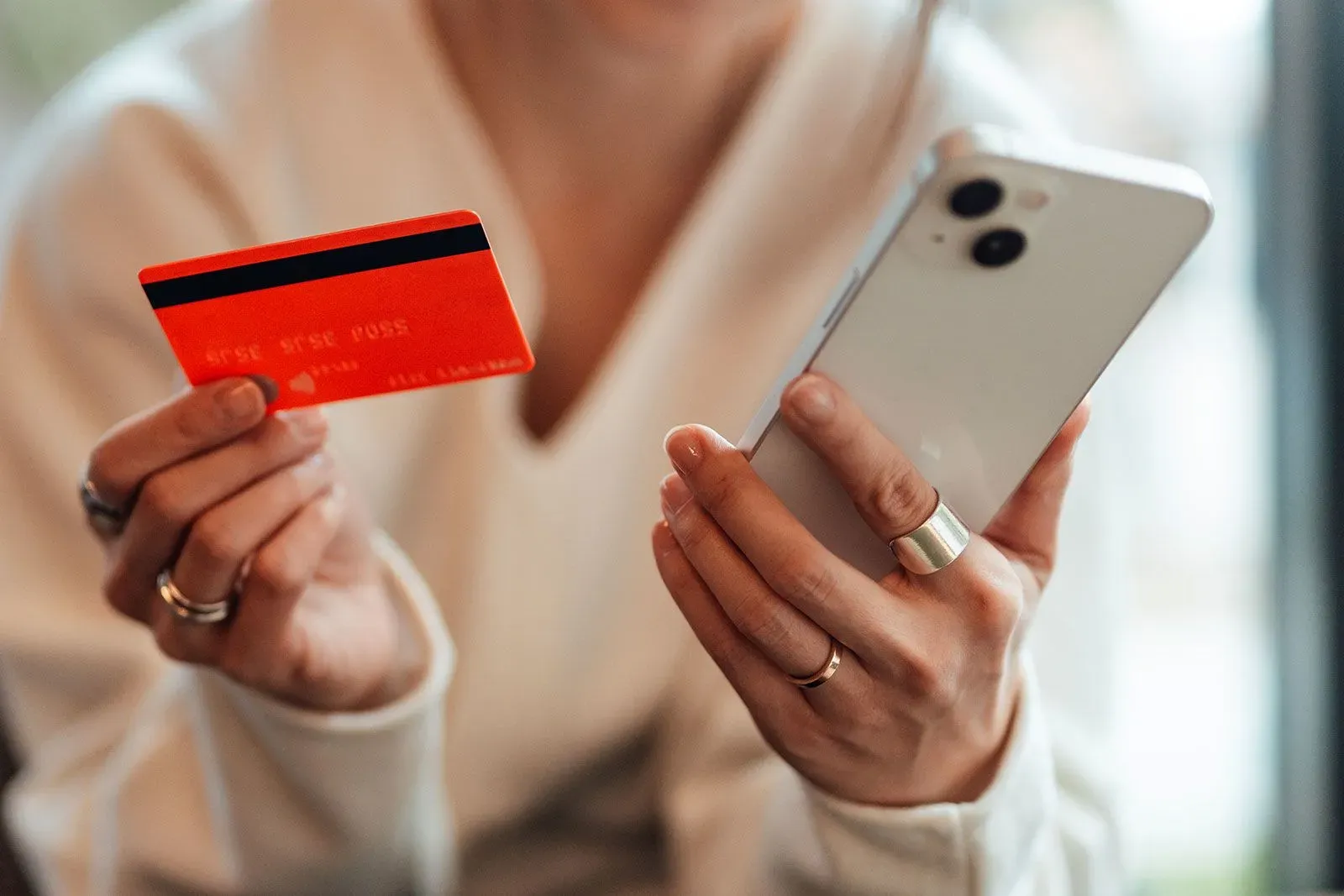 شخص يحمل بطاقة ائتمان حمراء وهاتفًا ذكيًا، يعكس الضغوط المالية التي يواجهها الأمريكيون، خاصة جيل Z بسبب ديون الطلاب.