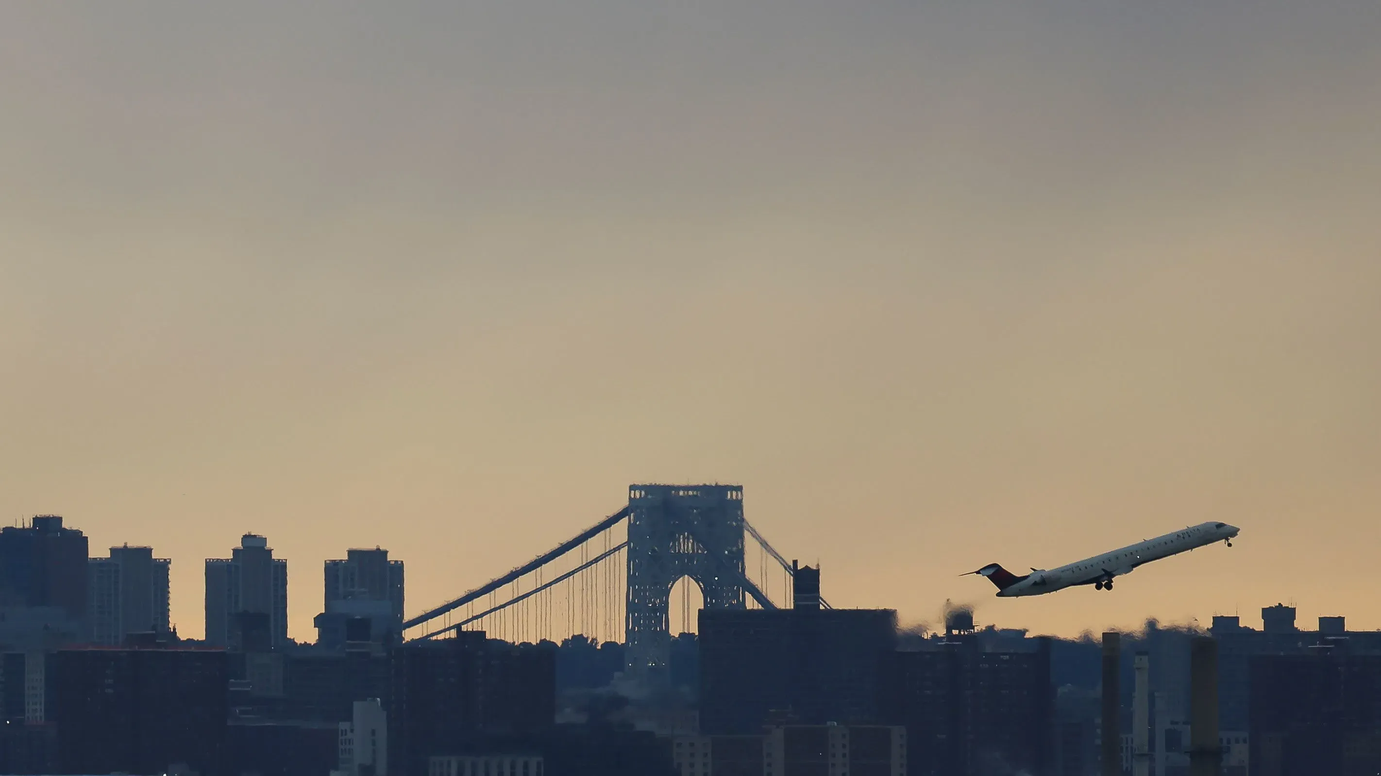 طائرة صغيرة تقلع فوق أفق مدينة نيويورك مع جسر جورج واشنطن في الخلفية، مما يعكس تأثير انقطاع نظام الإشعارات على الرحلات الجوية.