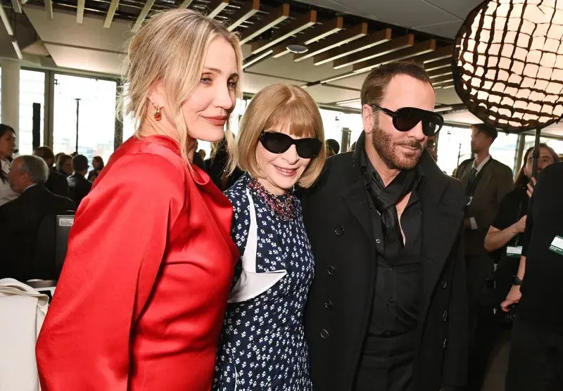 كيميرون دياز، آنا وينتور، وتوم فورد يتوسطون في حدث أسبوع الموضة في باريس، مرتدين نظارات شمسية، مع خلفية حديثة.