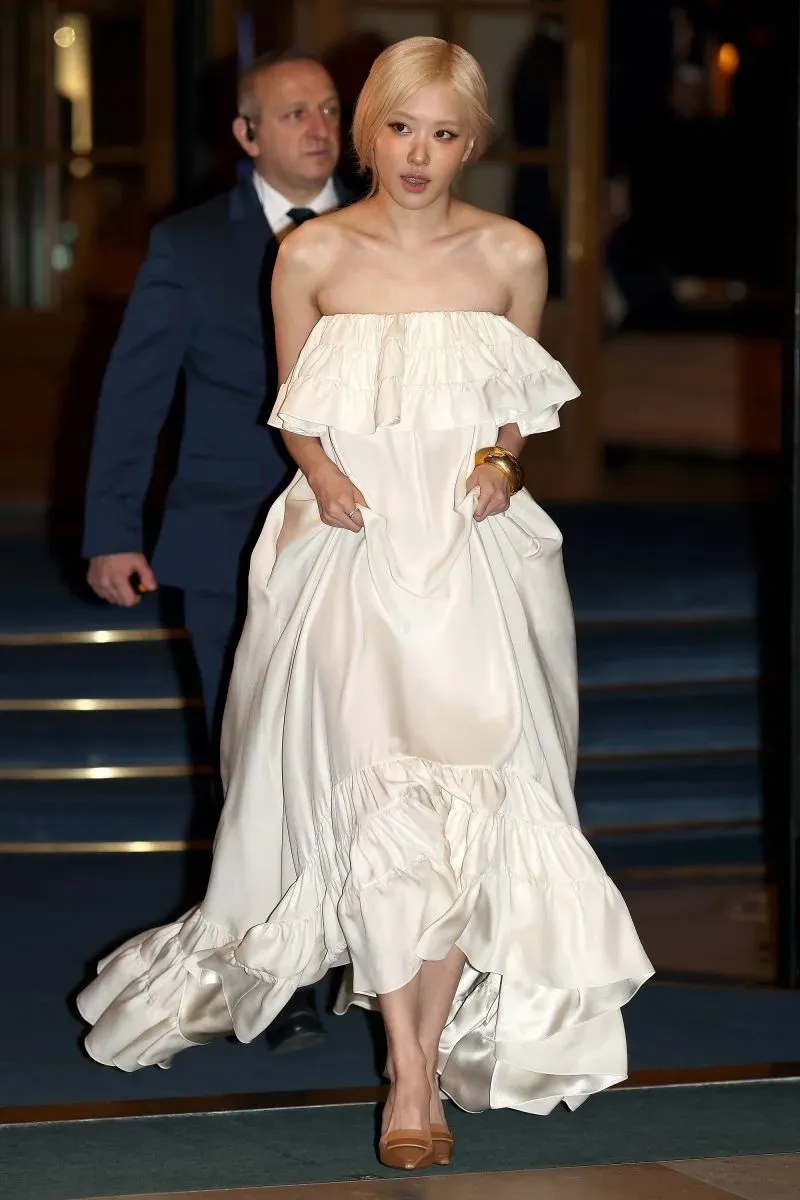 ظهور جيسو من بلاك بينك بفستان أبيض أنيق في حدث أسبوع الموضة بباريس، مع حارس شخصي خلفها.