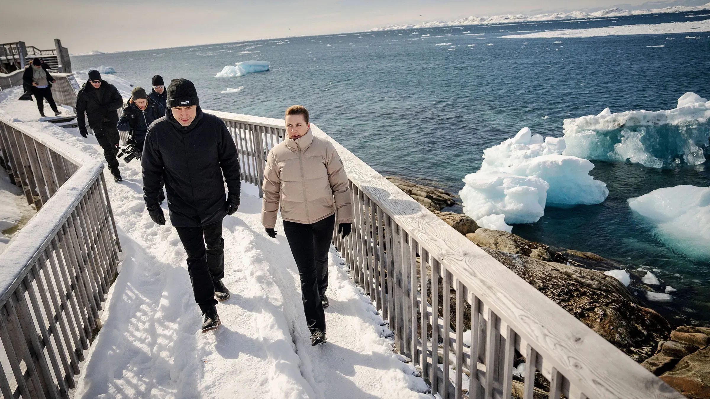 رئيسة الوزراء الدنماركية ميتي فريدريكسن تتجول في شوارع نوك بجانب زعيم غرينلاند ينس فريدريك نيلسن، وسط مشهد ثلجي وبحري.