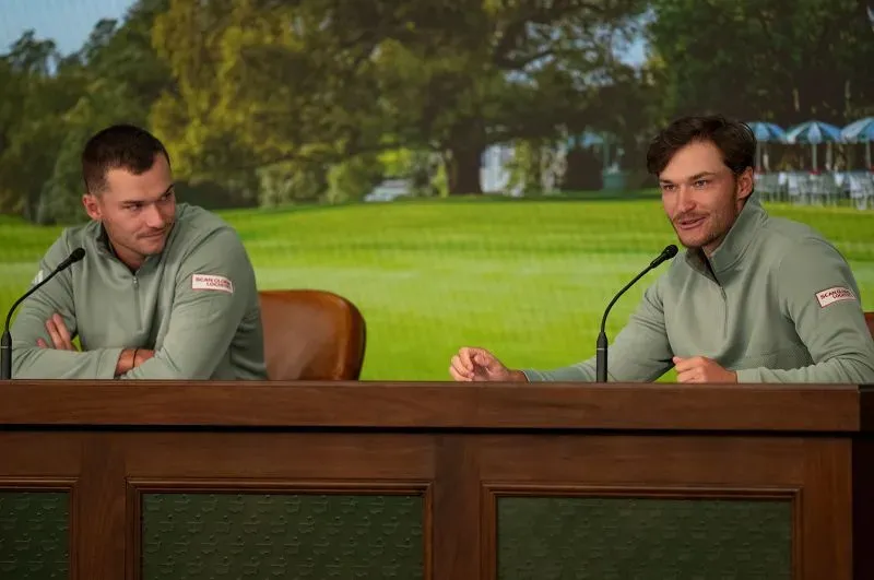 توأم هويغارد، نيكولاي وراسموس، يتحدثان خلال مؤتمر صحفي قبل بطولة الماسترز، مرتديين ملابس متشابهة، مع خلفية خضراء لمضمار الغولف.