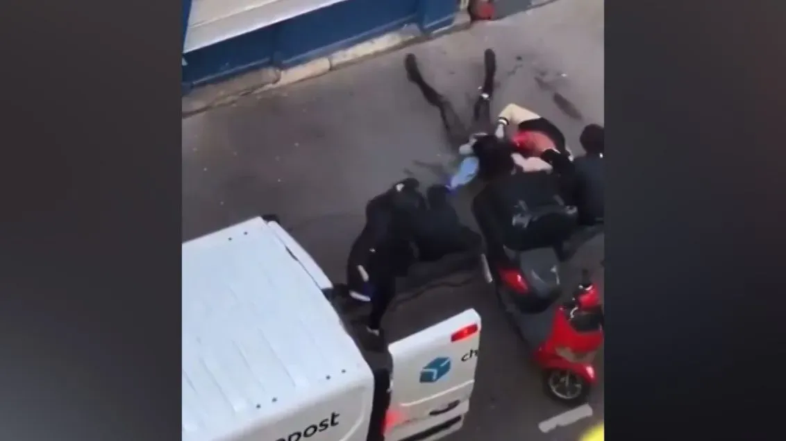 مشهد من هجوم مسلح في باريس حيث يحاول أربعة رجال ملثمون اختطاف امرأة وطفلها، بينما يتدخل المارة لإنقاذهم.