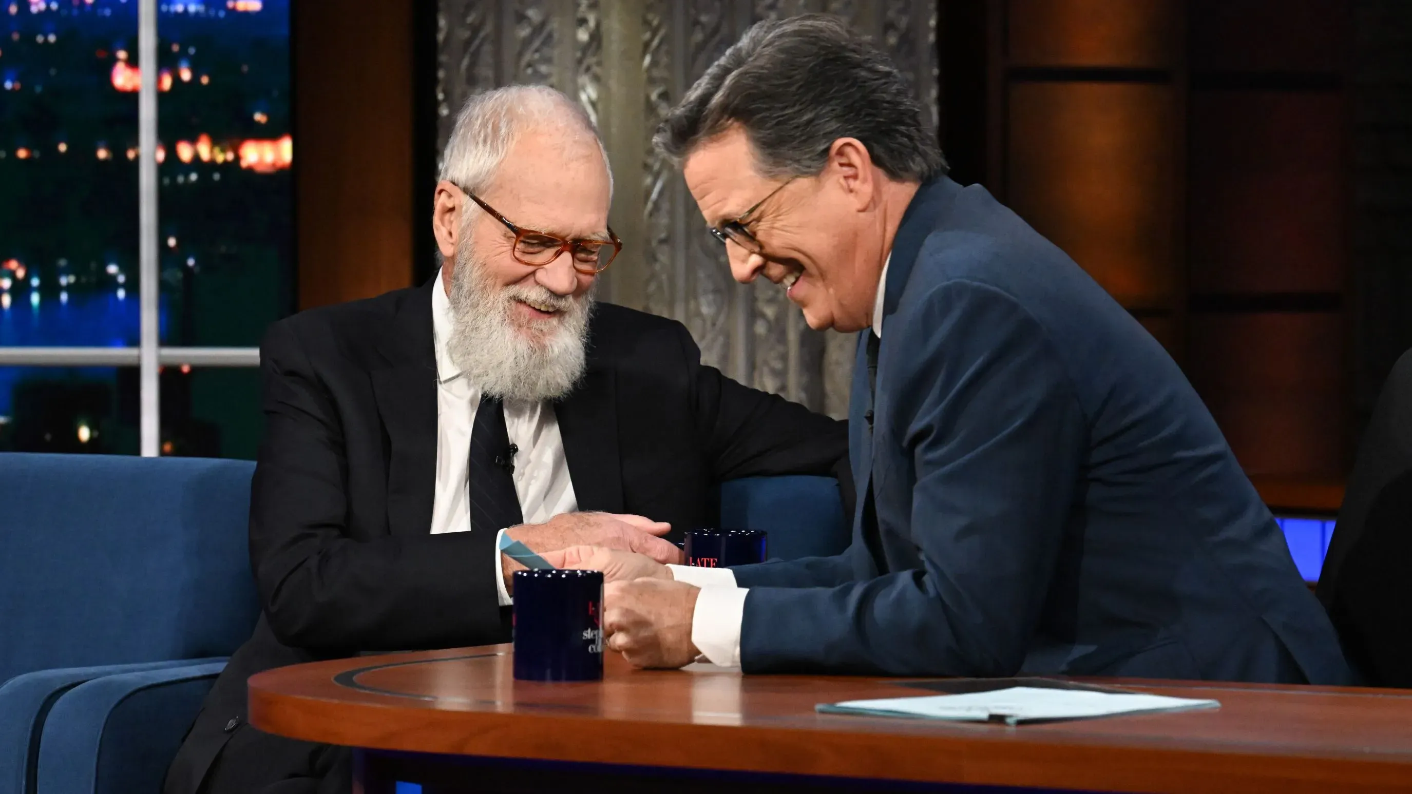 ديفيد ليترمان وستيفن كولبير يتبادلان الضحكات في برنامج "العرض المتأخر"، في لحظة ودية تعكس صداقتهما الطويلة.