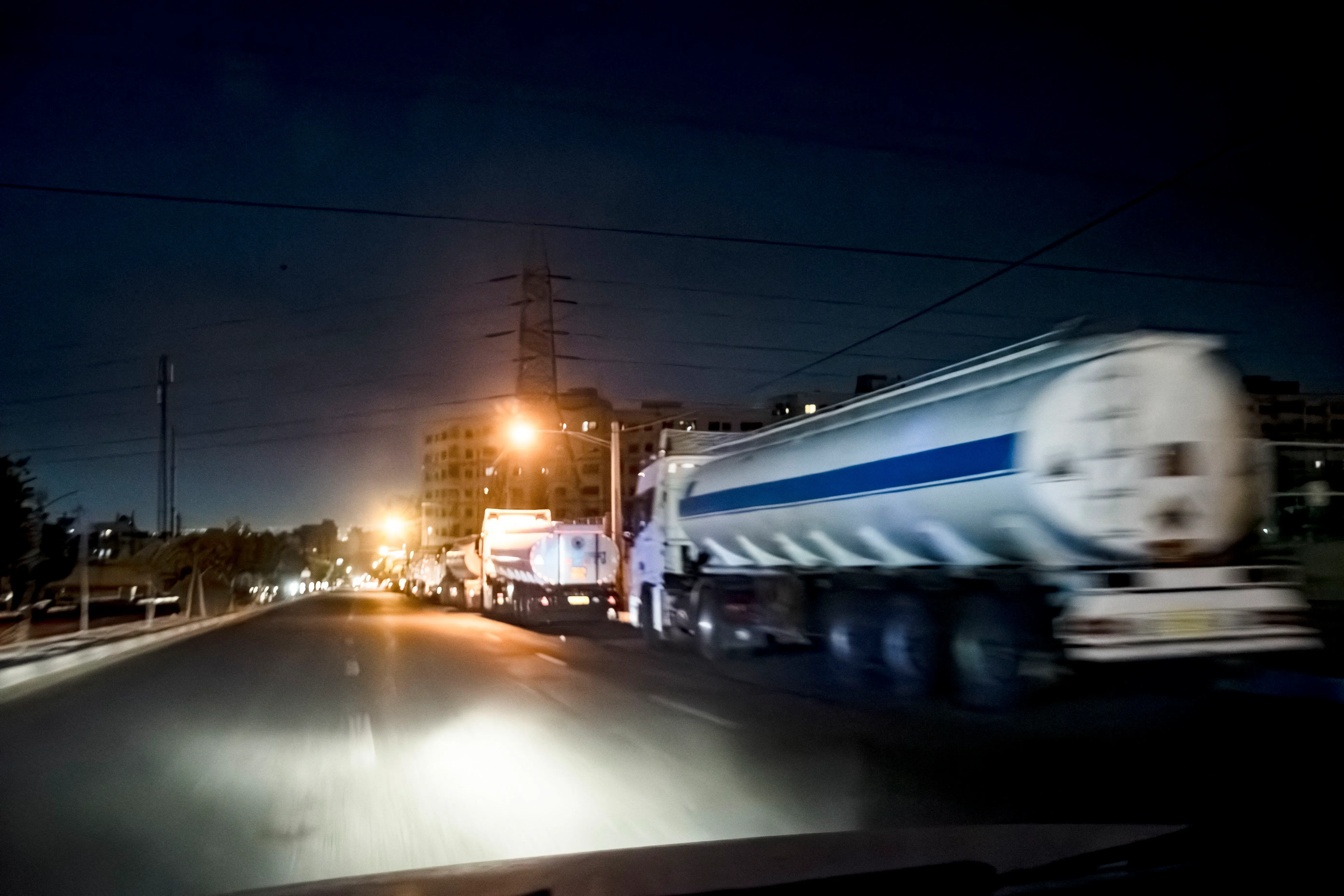 طابور من شاحنات المياه في طهران ليلاً، تعكس أزمة نقص المياه الحادة التي تواجه العاصمة الإيرانية.