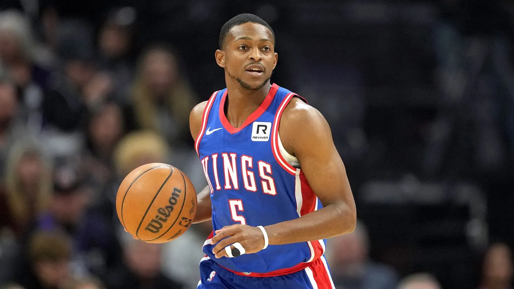 دي آرون فوكس، حارس فريق ساكرامنتو كينجز، يحمل كرة سلة، مع التركيز على انتقاله المحتمل إلى سان أنطونيو سبيرز.