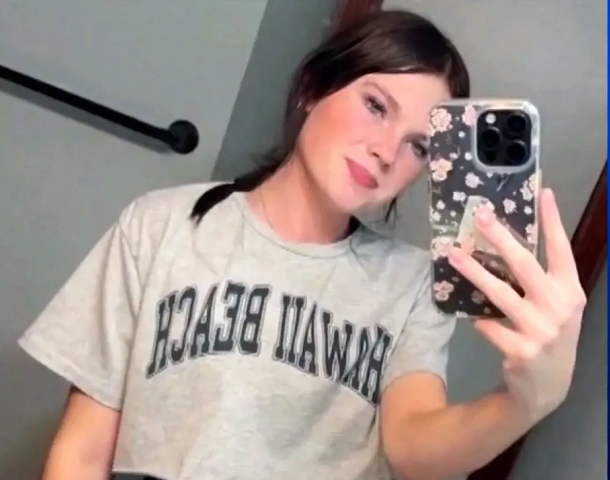 صورة لمراهقة تلتقط سيلفي، ترتدي قميصًا مكتوبًا عليه "هاواي بيتش"، تعكس لحظة من حياتها قبل الحادث المأساوي على متن سفينة سياحية.