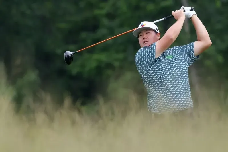 لاعب جولف يضرب الكرة في ملعب أوكمونت، محاط بالعشب الطويل. يُظهر التركيز والتحدي في بطولة الولايات المتحدة المفتوحة.