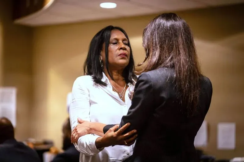 امرأة ترتدي قميصًا أبيض تتحدث مع امرأة أخرى في قاعة المحكمة، تعبيرات وجههما تعكس مشاعر التوتر والدعم خلال محاكمة متعلقة بقضية تايري نيكولز.