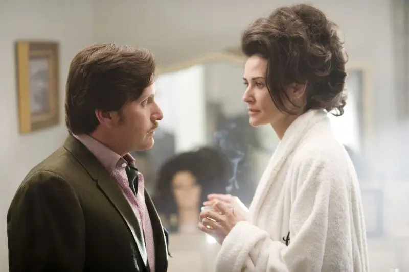 مشهد من فيلم "المادة" (2024) يظهر ديمي مور في دور نجمة هوليوود تتعامل مع تحديات الصناعة، مع شخصية أخرى تتحدث إليها في خلفية ضبابية.