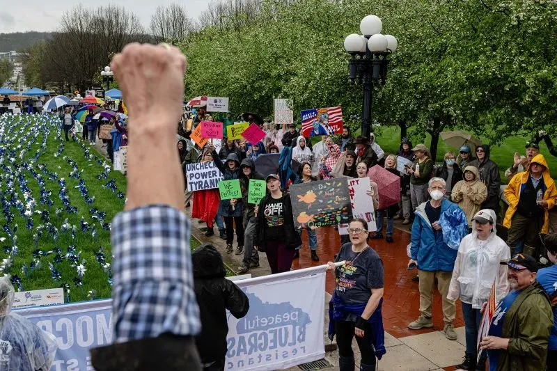 محتجون يحملون لافتات في تجمع عام، يعبرون عن آرائهم حول السياسة، مع أجواء مفعمة بالحماس والتضامن.