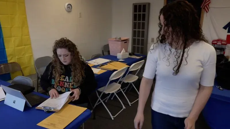 محتجون ديمقراطيون يعملون في مكتب انتخابي، مع تكدس مستندات وأدوات على الطاولة، يعكسون جهود الحزب لمواجهة تحديات ترامب.