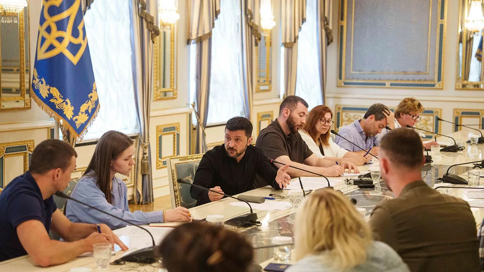 اجتماع في مكتب الرئيس الأوكراني، حيث يناقش الحضور قضايا حقوق الإنسان وتبادل السجناء، مع العلم الأوكراني في الخلفية.