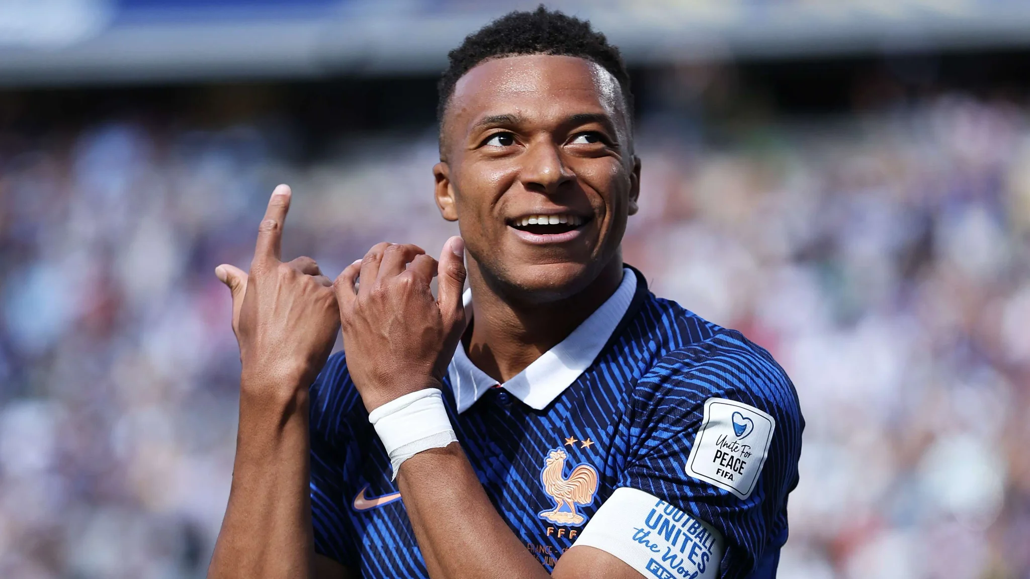 كيليان مبابي يرتدي زي منتخب فرنسا الأزرق ويحتفل بهدف خلال مباراة دولية، مع التركيز على طموحه للفوز بدوري أبطال أوروبا مع ريال مدريد.