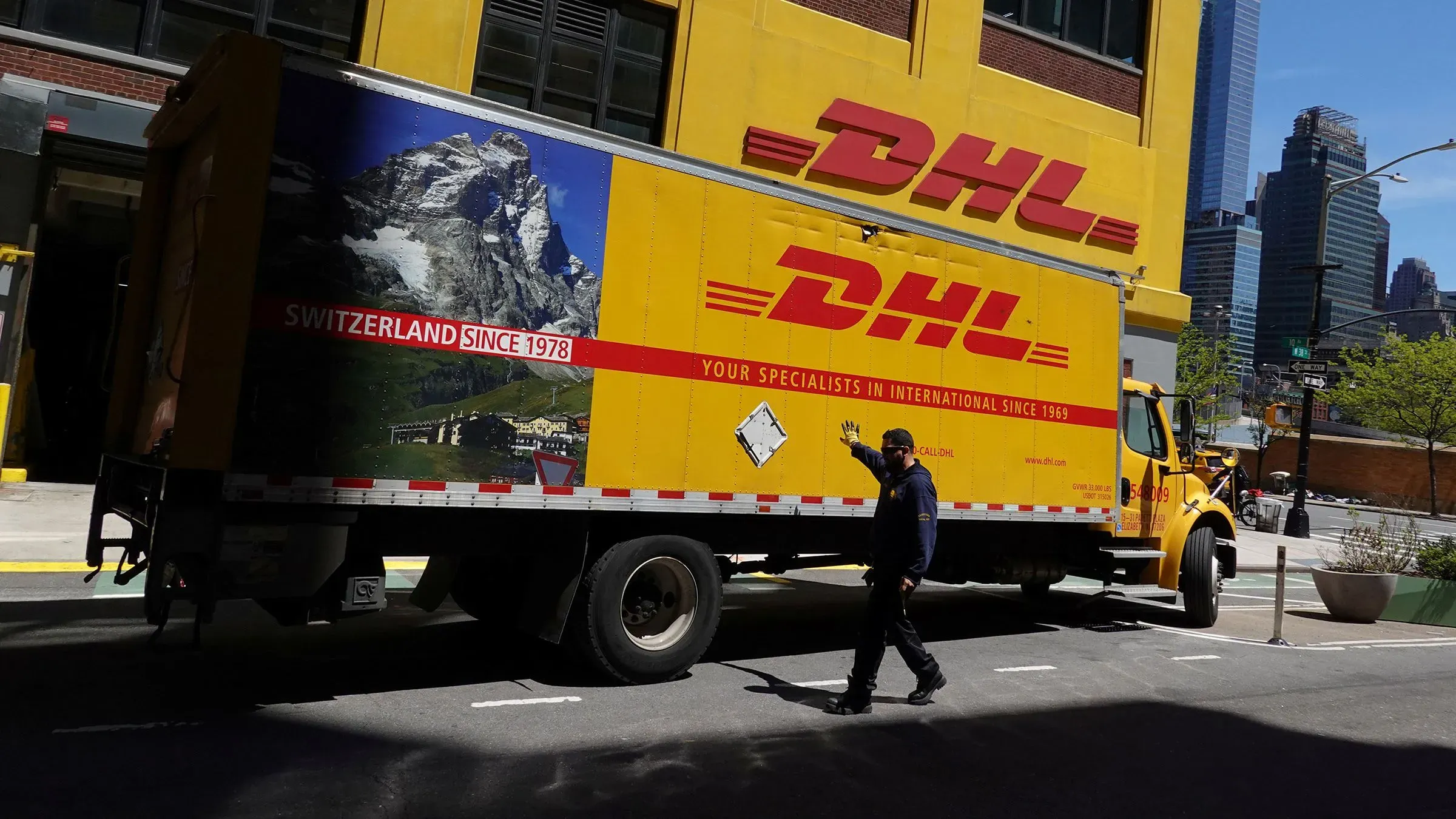 شاحنة DHL في مدينة نيويورك، مع شعار الشركة، أثناء تحميل أو تفريغ الشحنات في ظل تغييرات الجمارك الأمريكية.