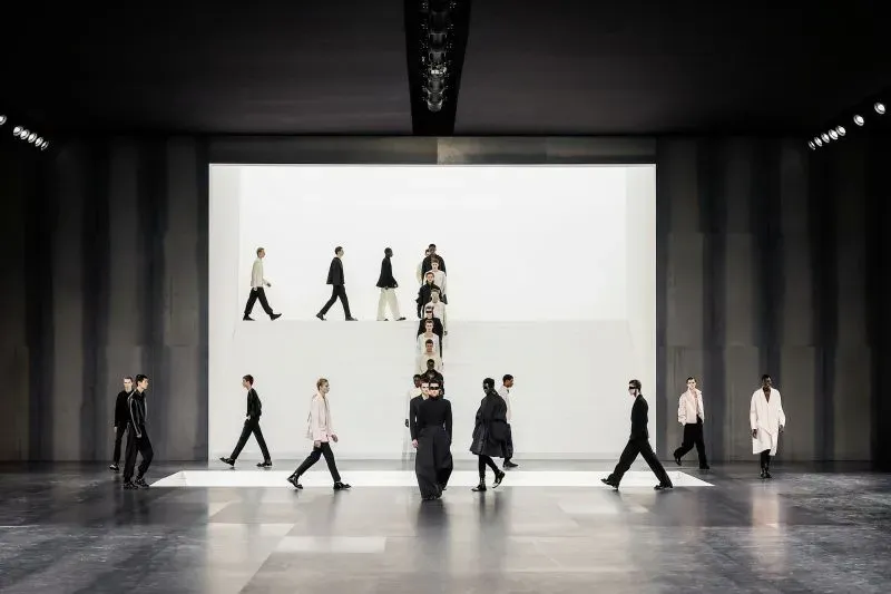 عرض أزياء لدار ديور للأزياء الرجالية، حيث يسير عارضون في تصاميم متنوعة على منصة حديثة.
