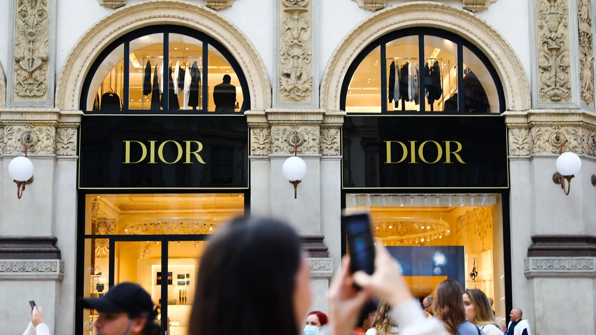 واجهة متجر ديور الفاخرة تُظهر لافتة العلامة التجارية، مع وجود زبائن يتجولون في المنطقة، تعكس التزام ديور بالشفافية في سلسلة التوريد.