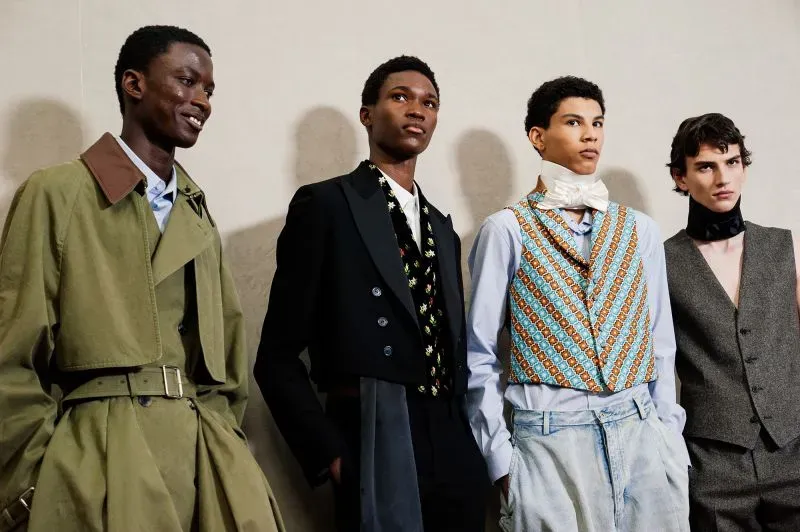 أربعة عارضين أزياء يرتدون ملابس متنوعة تعكس تصاميم عصرية وأنيقة، مع التركيز على الألوان والقصات الفريدة في أسبوع الموضة بباريس.