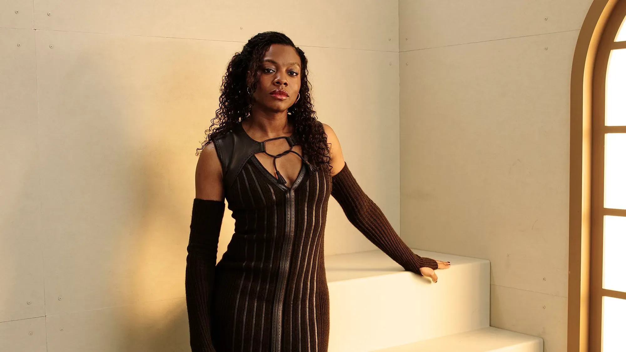 نيا داكوستا، المخرجة الأمريكية، تقف على درجات في موقع تصوير، مرتدية فستانًا أسود ضيقًا، تعكس ثقتها وإنجازاتها في صناعة الأفلام.