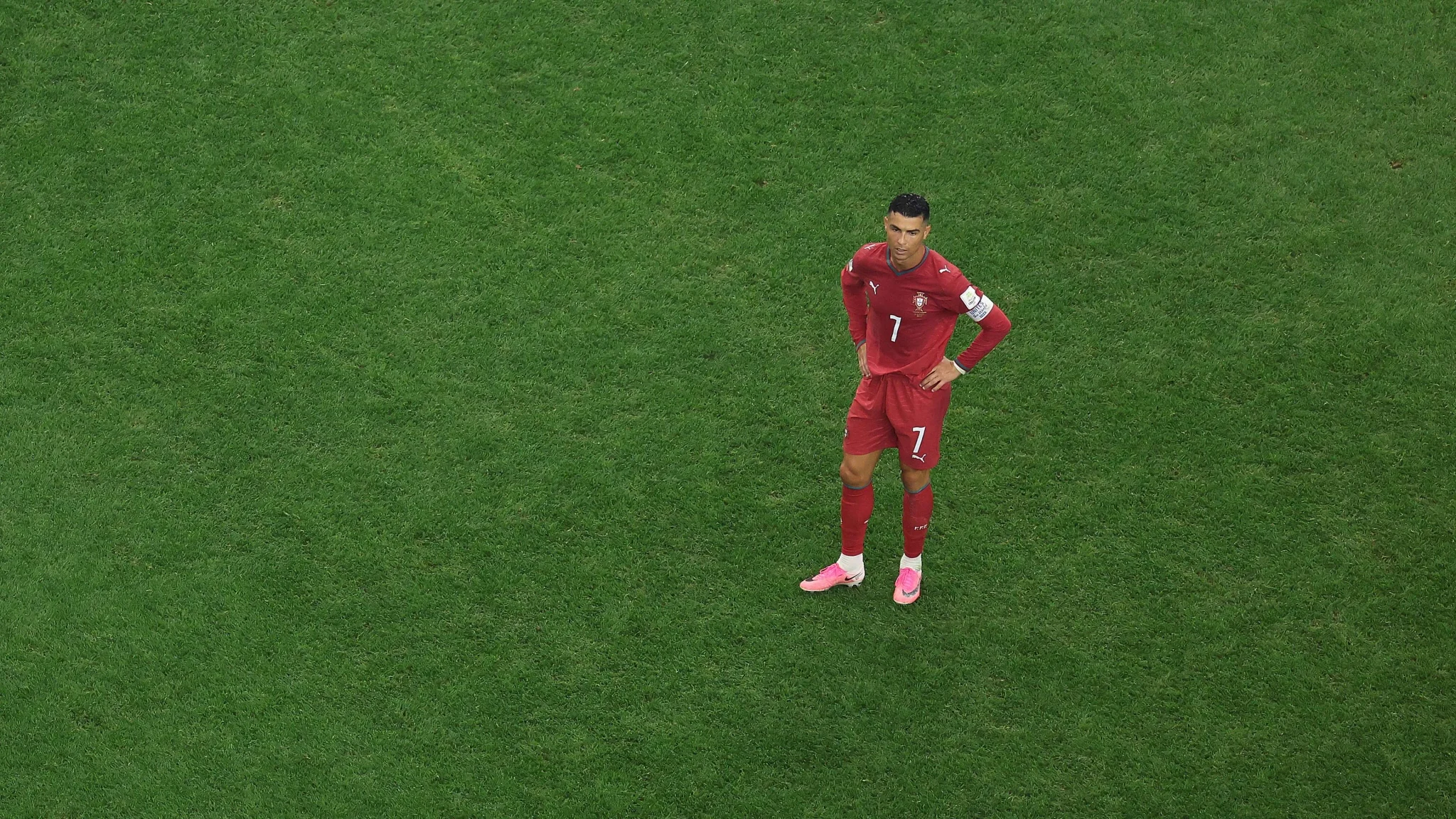 كريستيانو رونالدو يرتدي زي منتخب البرتغال الأحمر يقف بمفرده على أرضية الملعب الأخضر خلال مباراة دولية.