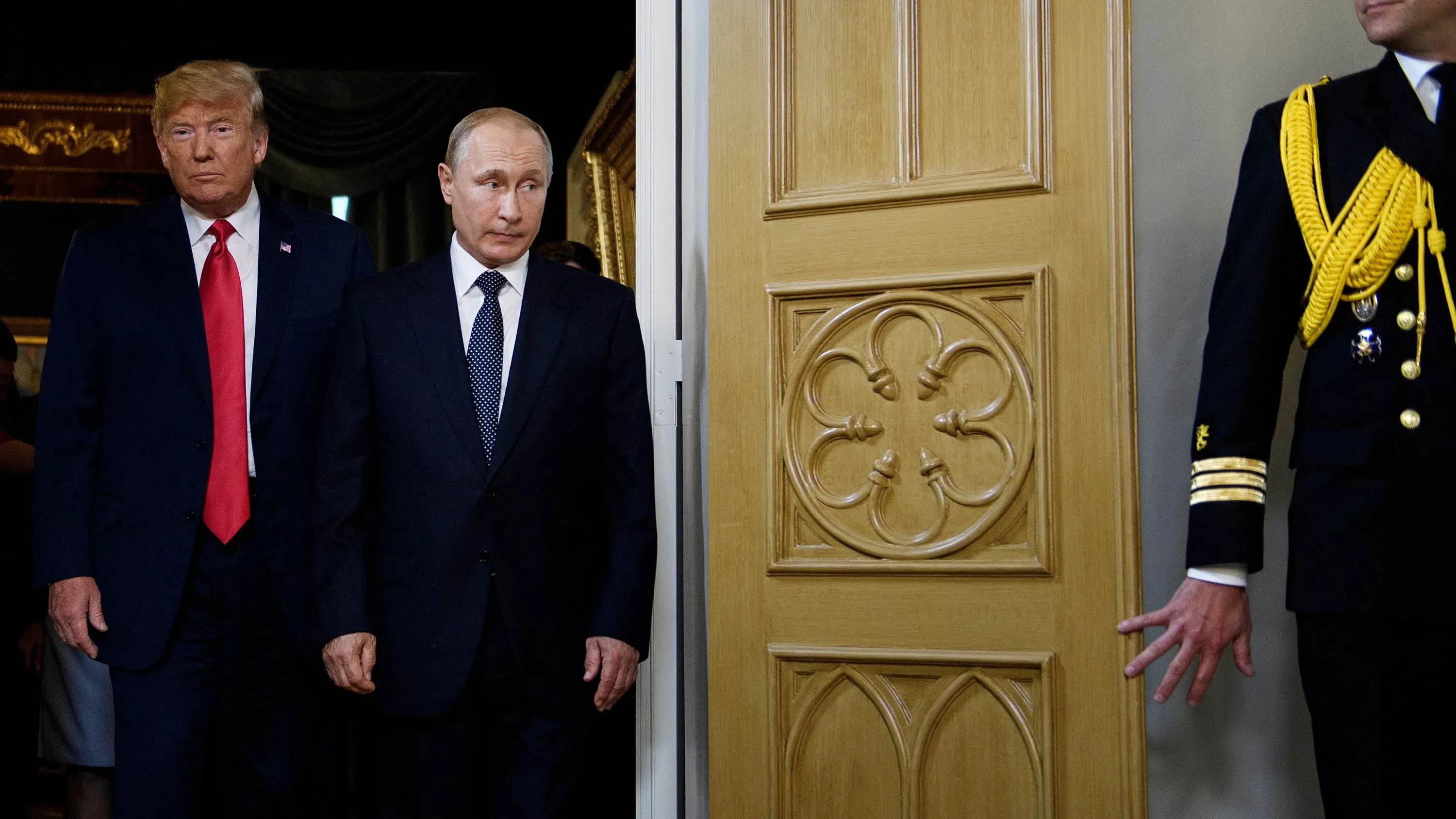 ترامب وبوتين يسيران معًا، حيث يظهر ترامب في بدلة داكنة وربطة عنق حمراء، بينما بوتين يرتدي بدلة داكنة وقميص أبيض، في سياق توتر سياسي.