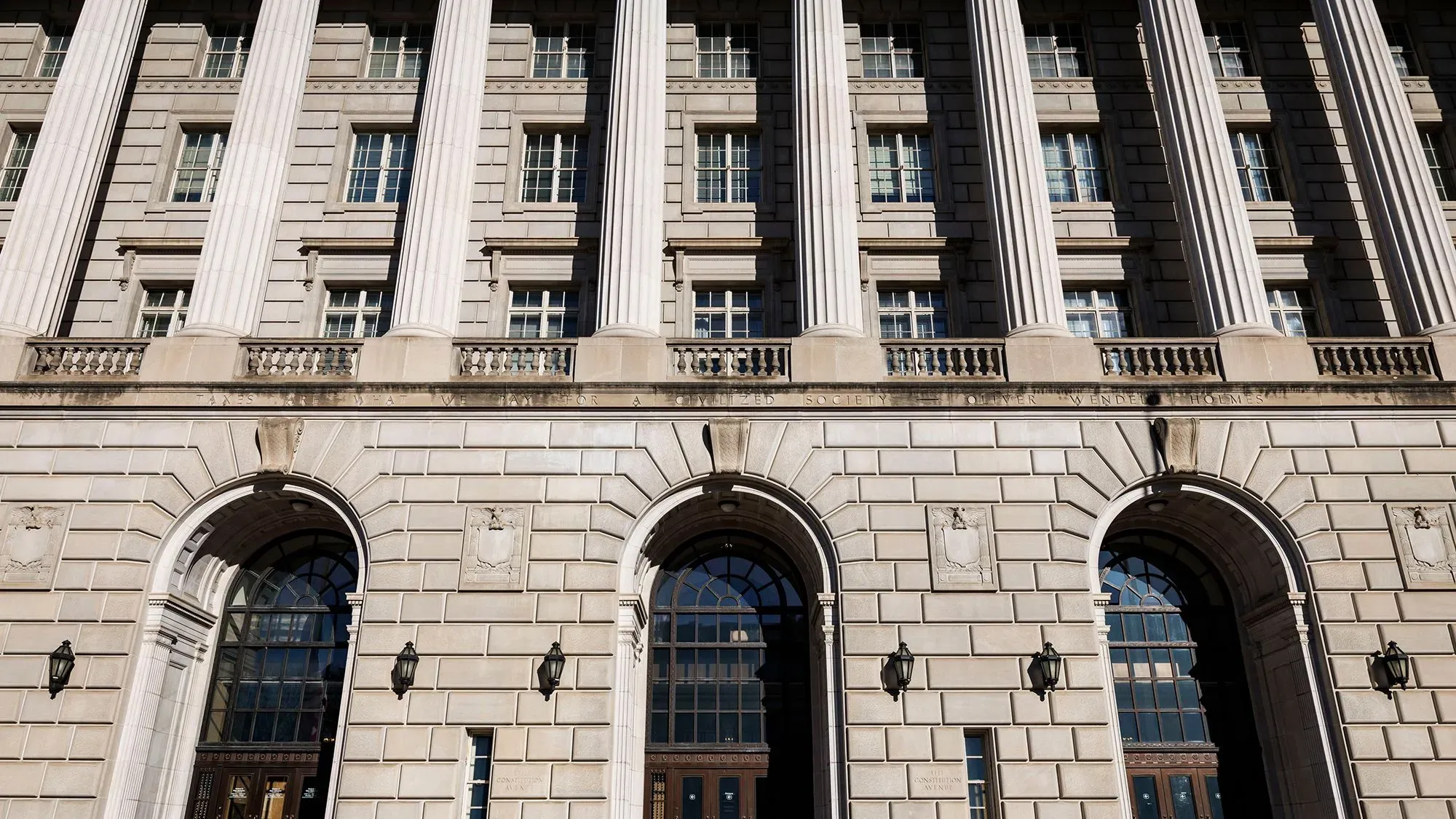 واجهة مبنى دائرة الإيرادات الداخلية الأمريكية، تظهر الأعمدة المعمارية والنوافذ الكبيرة، تعكس أهمية النظام الضريبي في إدارة البيانات الحساسة.