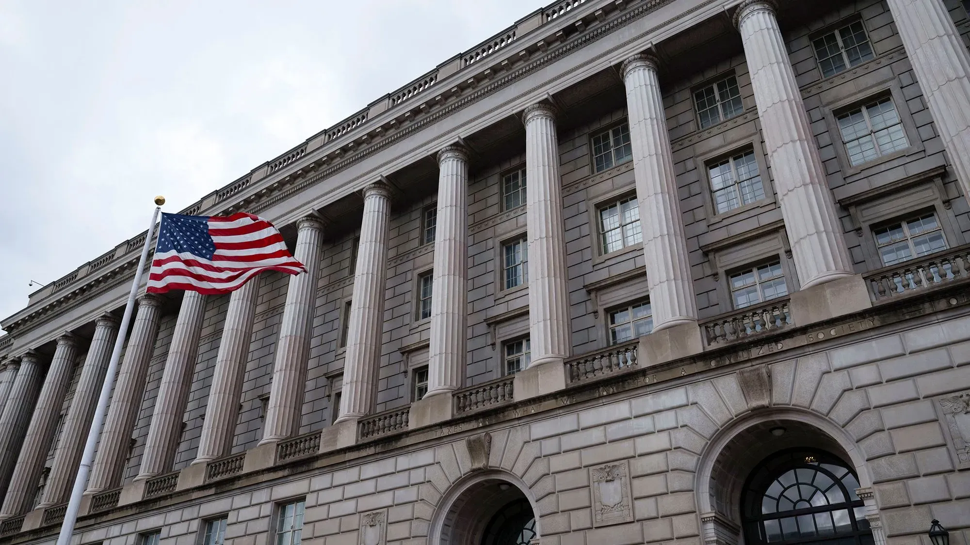 مبنى مصلحة الضرائب الأمريكية مع العلم الأمريكي يرفرف أمامه، في سياق الجدل حول وصول DOGE إلى أنظمة البيانات الضريبية.