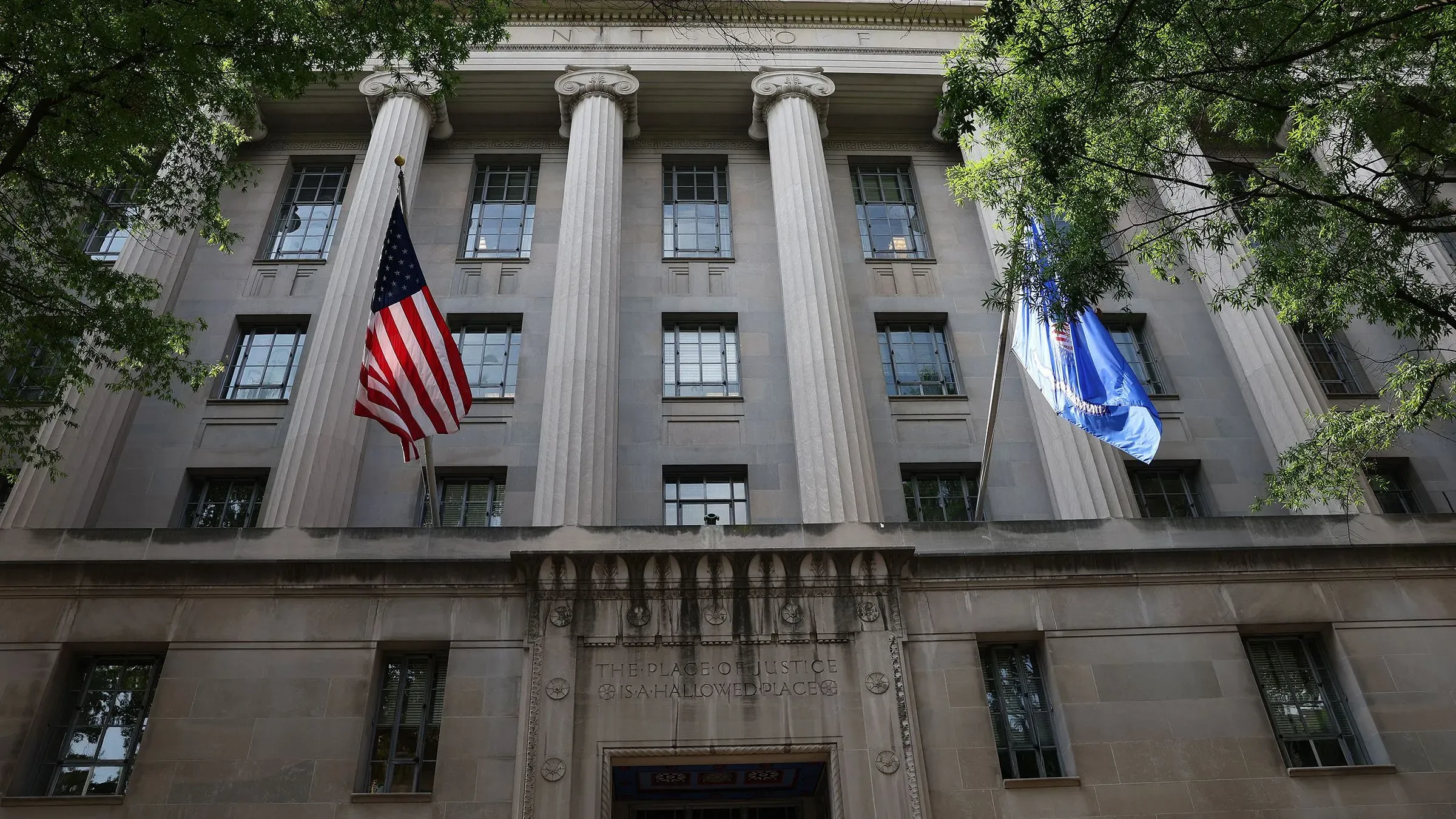 واجهة وزارة العدل الأمريكية مع أعلام ترفرف، تعكس الأجواء القانونية المحيطة بقضية ترحيل خاطئة لأبريغو غارسيا.