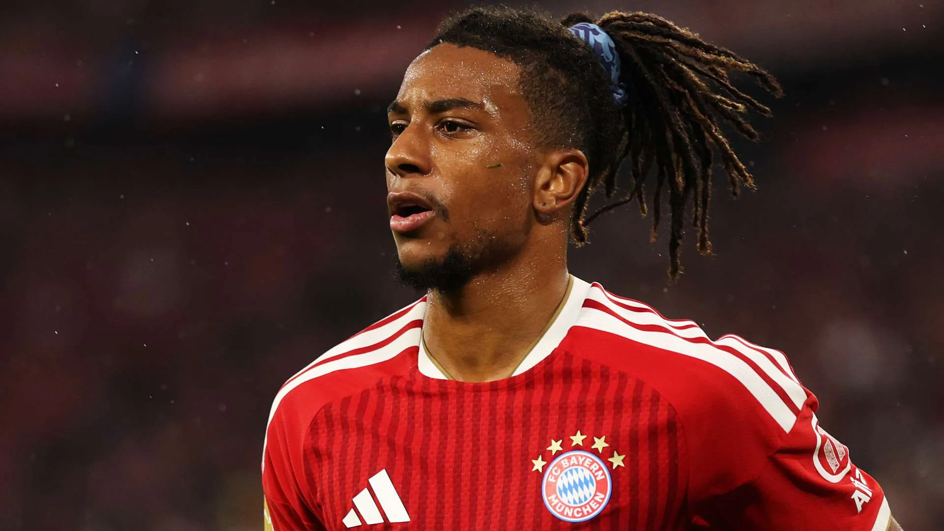 لاعب بايرن ميونخ أوليس يرتدي قميص الفريق الأحمر خلال مباراة، مع تركيز على وجهه وتفاصيل تسريحة شعره المميزة.