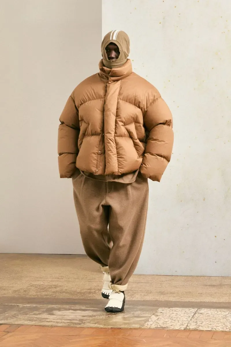 موديل يرتدي سترة ضخمة بلون بني مع بنطال مريح، مظهر يجسد تنسيق الأزياء السخية لعروض ميلانو للخريف والشتاء 2025.