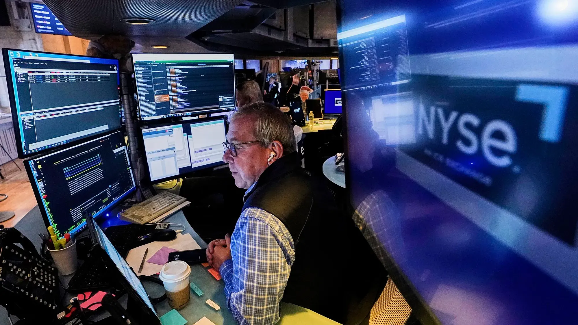 تاجر في سوق الأسهم يعمل أمام شاشات متعددة تعرض بيانات السوق، مع التركيز على نشاط التداول بعد تقرير الوظائف القوي.