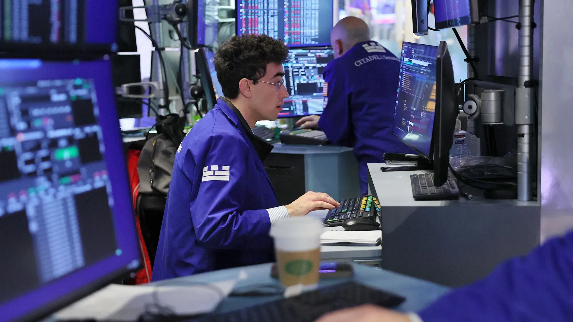 متداول في سوق الأسهم يجلس أمام شاشات تعرض بيانات مالية، مع تركيز على تحركات السوق بعد تخفيف التوترات التجارية بين الولايات المتحدة والصين.