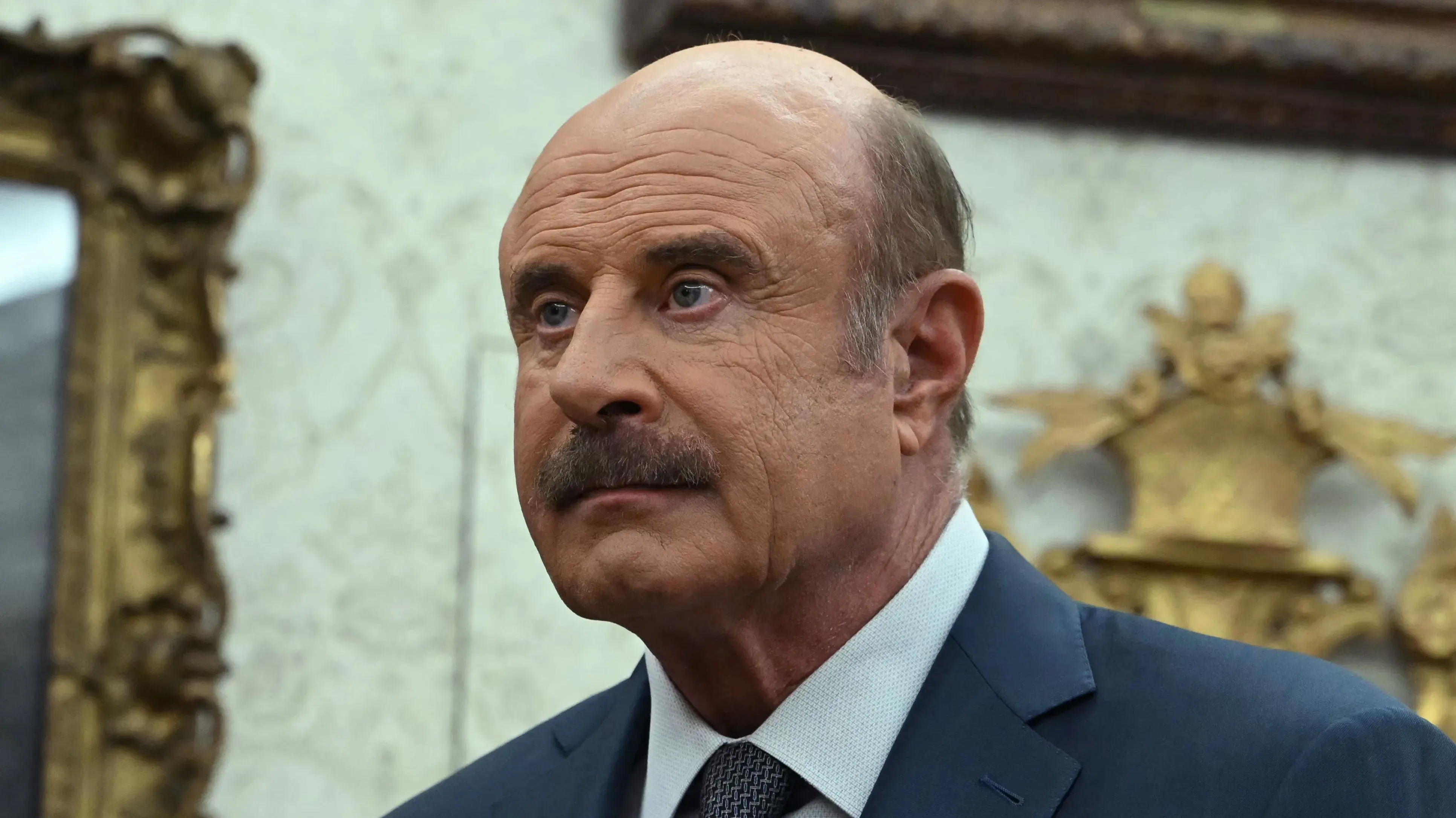 الدكتور فيل ماكجرو، الشخصية التلفزيونية، يظهر في لوس أنجلوس خلال حملة مثيرة للجدل ضد المهاجرين، محاطًا بأجواء توتر واحتجاجات.