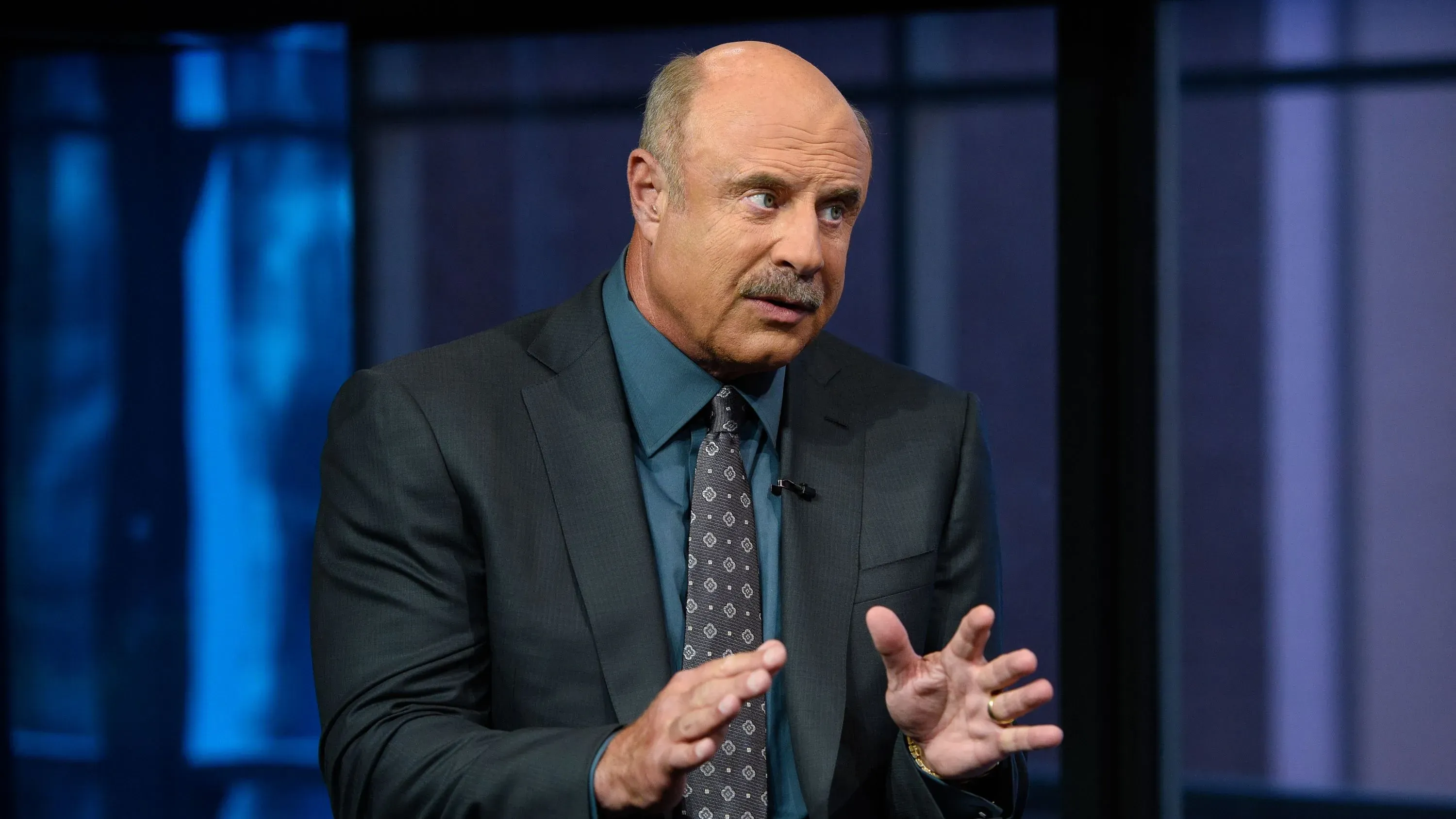 الدكتور فيل يتحدث بجدية خلال مقابلة، مع التركيز على قضايا الشبكة التلفزيونية الجديدة ميريت ستريت وتحدياتها القانونية.