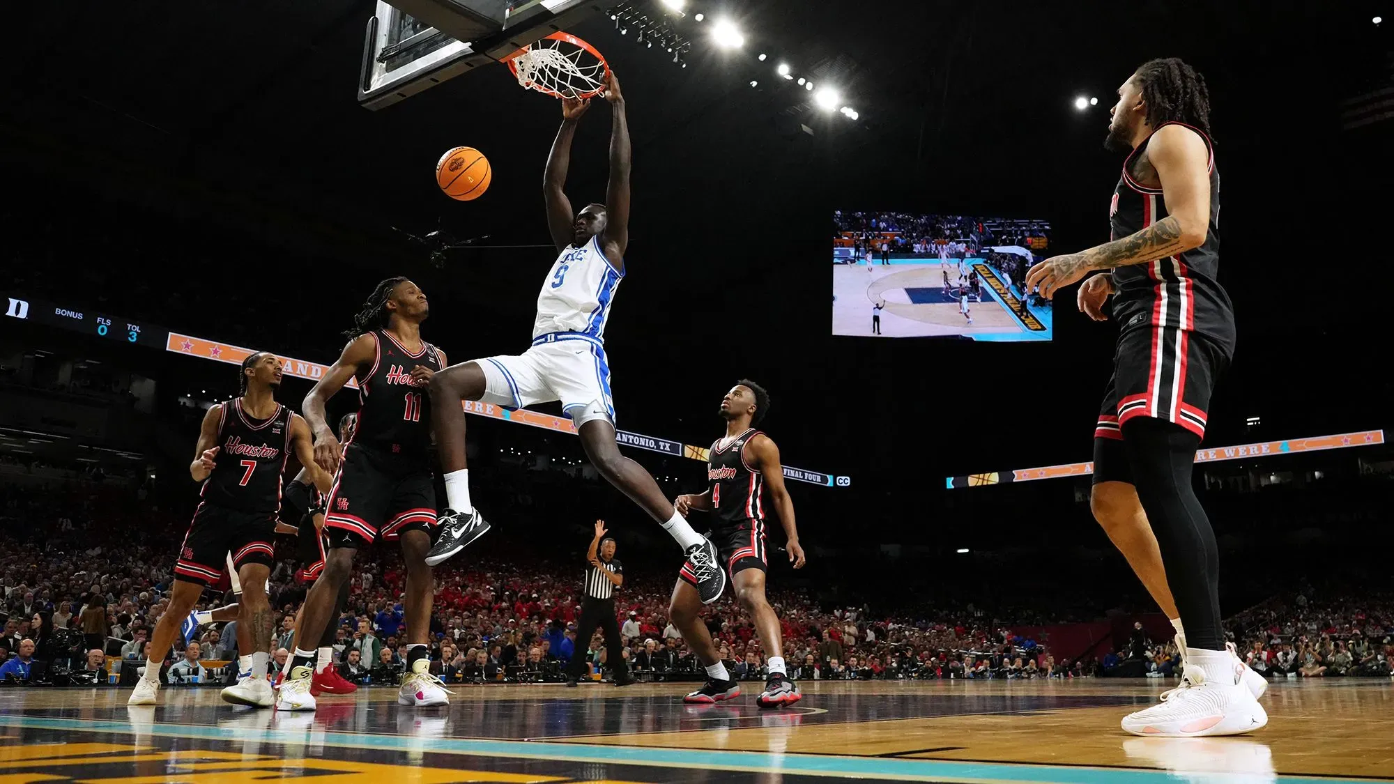 يظهر لاعب كرة السلة خامان مالواش من فريق ديوك وهو يسجل نقطة خلال مباراة، مع لاعبين آخرين في الخلفية.