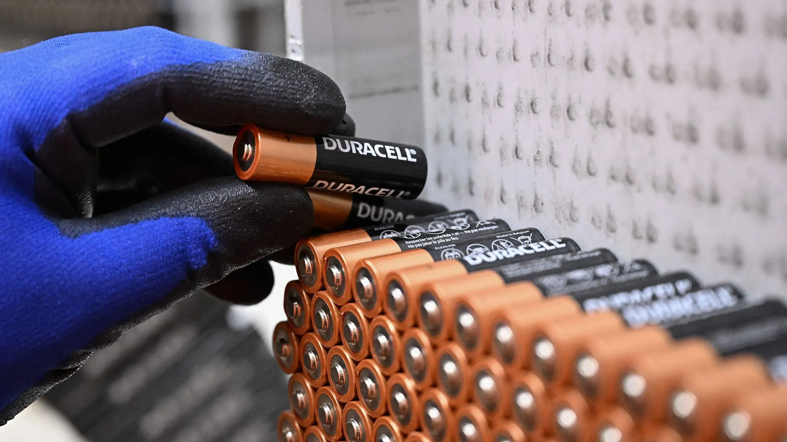 يد تحمل بطارية دوراسيل، مع ترتيب لبطاريات أخرى على الرف، في سياق النزاع القانوني مع إنرجايزر حول ادعاءات عمر البطارية.