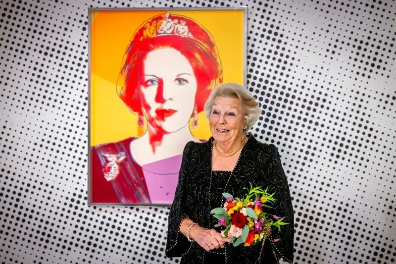 ملكة هولندا السابقة بياتريكس تظهر في خلفية ملونة، بينما امرأة تحمل باقة من الزهور تبتسم أمام صورة أندي وارهول.