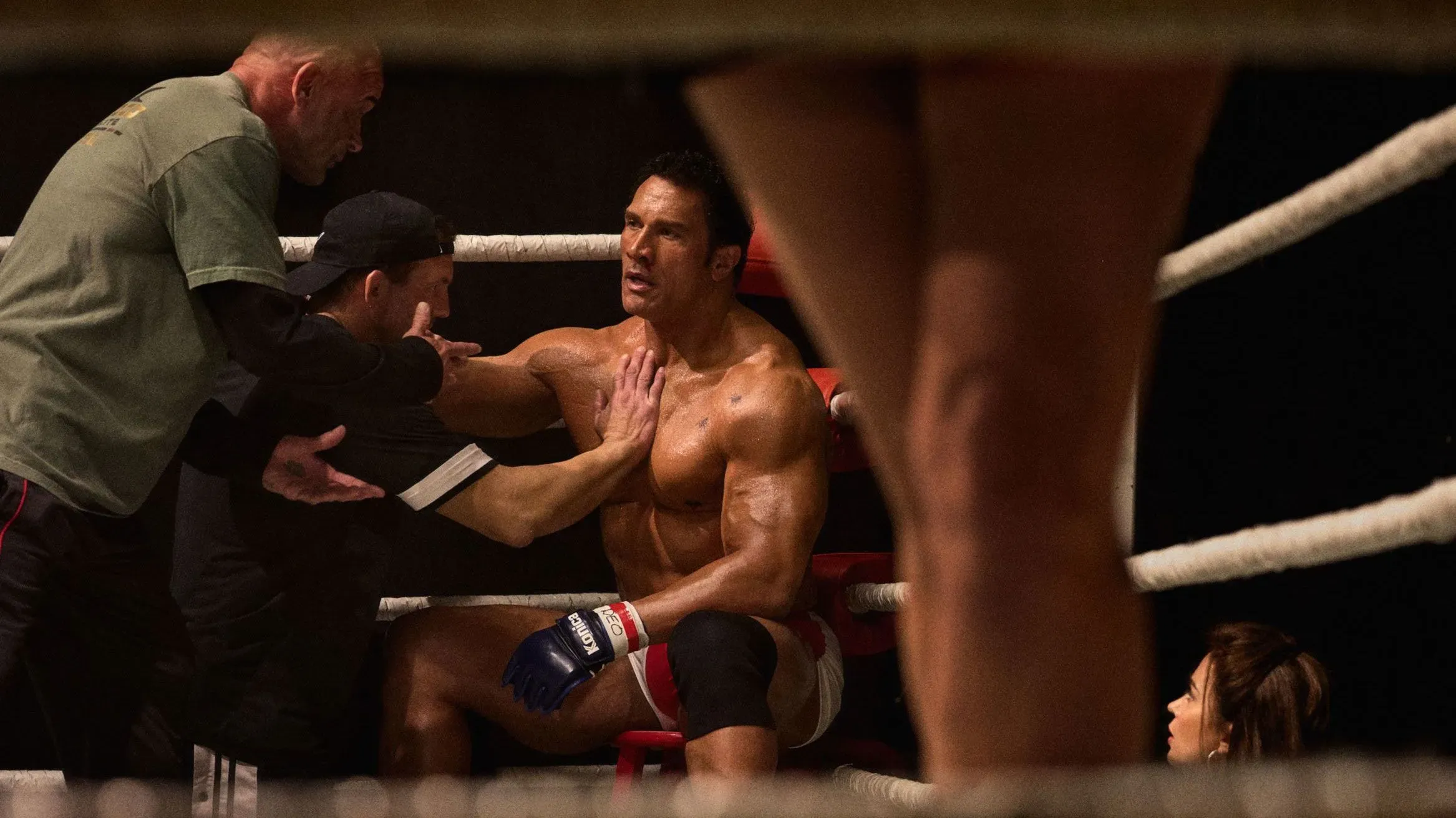 مشهد من فيلم "The Smashing Machine" يظهر مقاتلاً يجلس في زاوية الحلبة مع مدربه، مع التركيز على معاناته الجسدية والعاطفية.