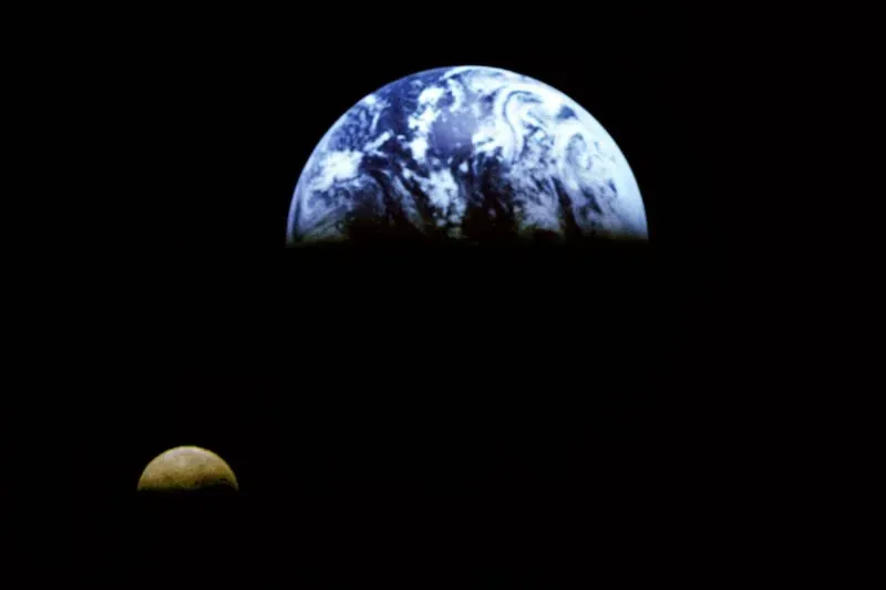 صورة تُظهر كوكب الأرض مع القمر في الفضاء، مع التركيز على تفاصيل السطح المائي والجبلي للأرض. تعكس الصورة موضوع سرعة دوران الأرض وتأثيراتها.