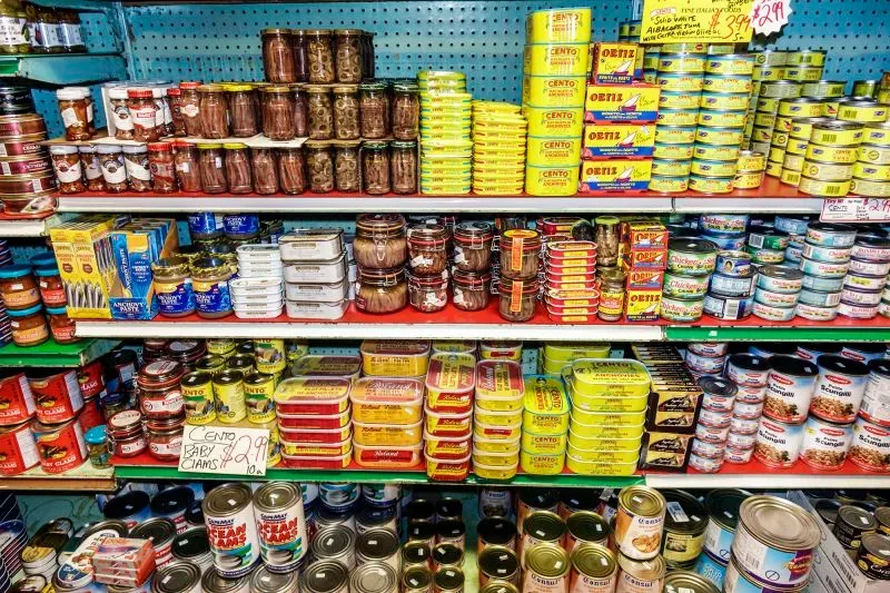 رفوف مليئة بعلب السمك المعلب، تشمل السردين والماكريل، تظهر تنوع الخيارات المتاحة للمستهلكين في ظل تزايد شعبية الأسماك المعلبة.