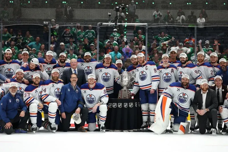 فريق إدمونتون أويلرز يحتفل بفوزهم بكأس المؤتمر الغربي، محاطين بالكأس ومشجعين في الخلفية، بعد تأهلهم إلى نهائي كأس ستانلي.