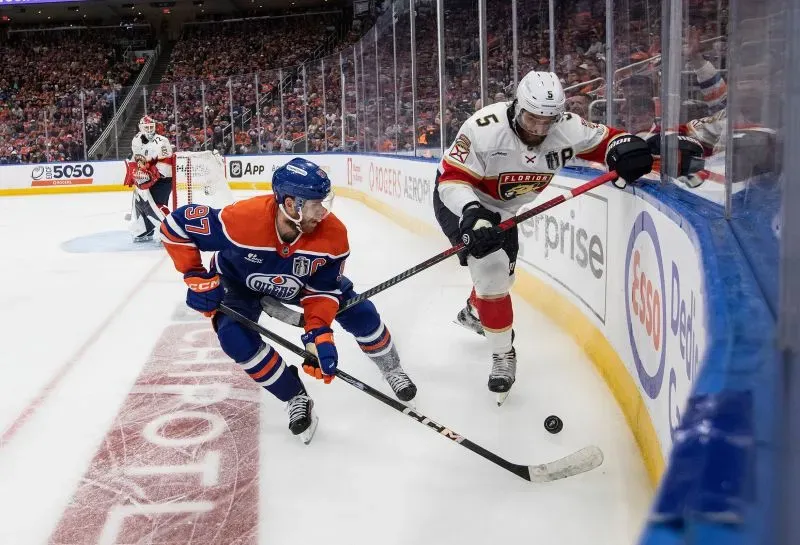 لاعبو هوكي من فريق إدمونتون أويلرز وفريق فلوريدا بانثرز يتنافسون على القرص في نهائي كأس ستانلي، مع جمهور متحمس في الخلفية.