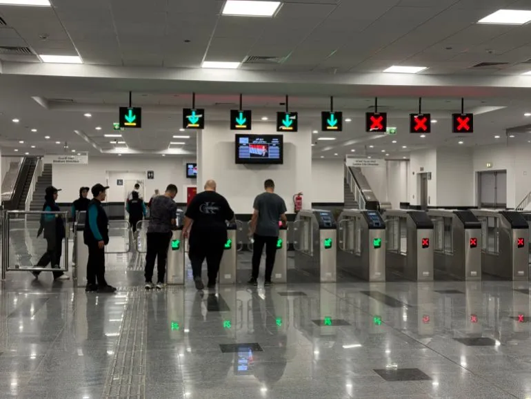 محطة مونوريل شرق النيل، حيث يظهر الركاب وهم يستخدمون بوابات الدخول، مع إشارات ضوئية توضح حالة الرحلات.
