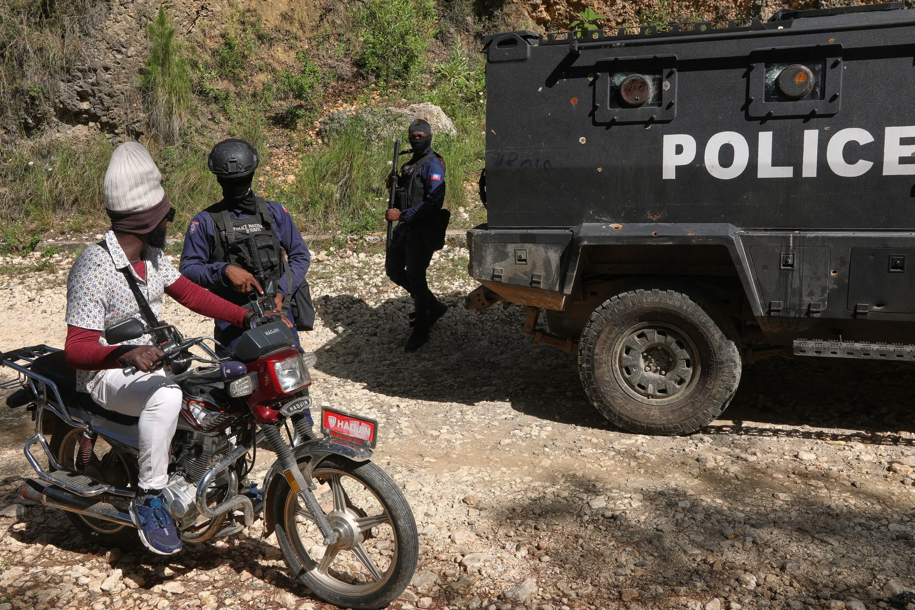 مسلح على دراجة نارية بالقرب من مركبة شرطة في هايتي، حيث تواصل السلطات جهودها للبحث عن المفقودين بعد اختطاف دار الأيتام.