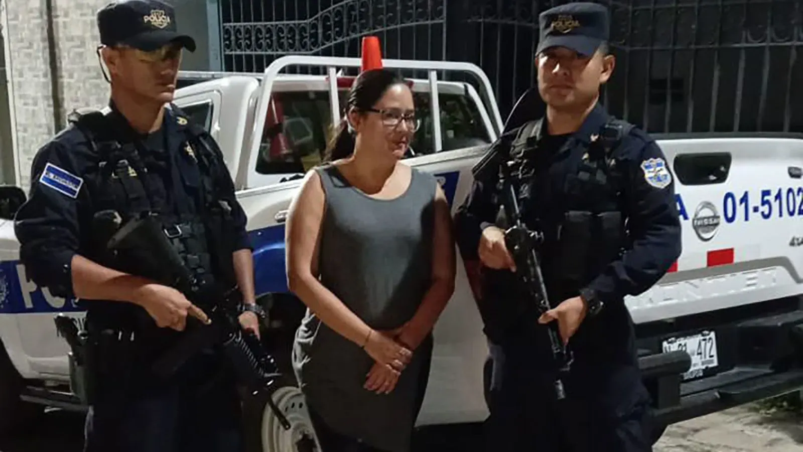 احتجاز المحامية روث إليونورا لوبيز، الناشطة الحقوقية، بين شرطيين مسلحين أمام مركبة للشرطة، في سياق انتقادات للحكومة السلفادورية.