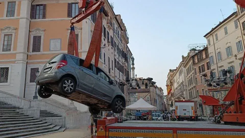 سيارة مرسيدس-بنز رمادية تُرفع بواسطة رافعة خلال عملية إنقاذ بعد أن علقت على السلالم الإسبانية في روما، حيث كان السائق قد ضل الطريق.